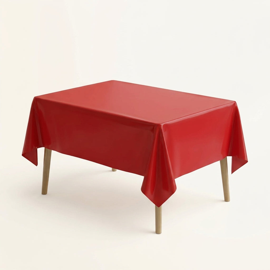 Red plastic party table cover on a rectangular table against a plain background